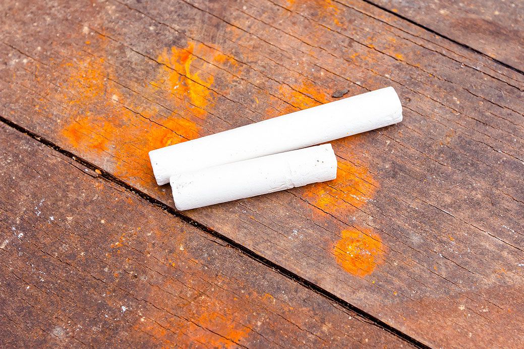 An image of two pieces of chalk on a wooden floor