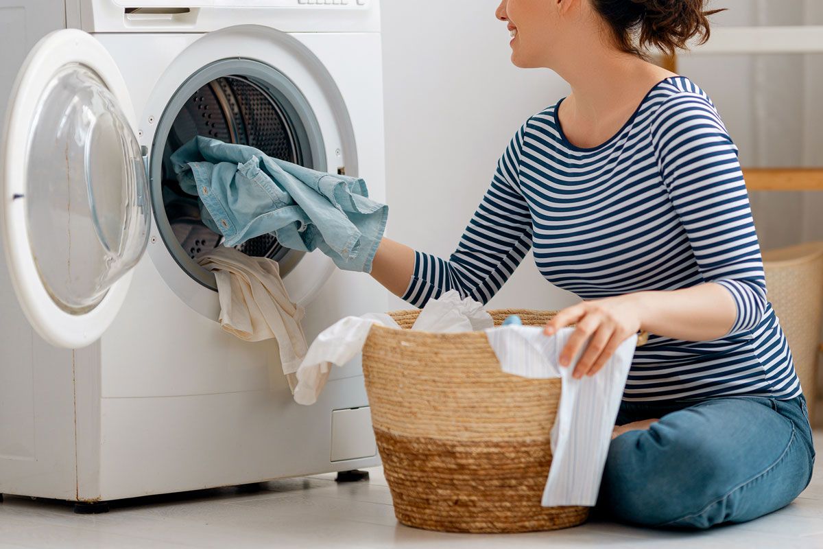 An image of a woman taking clothes out of the dryer