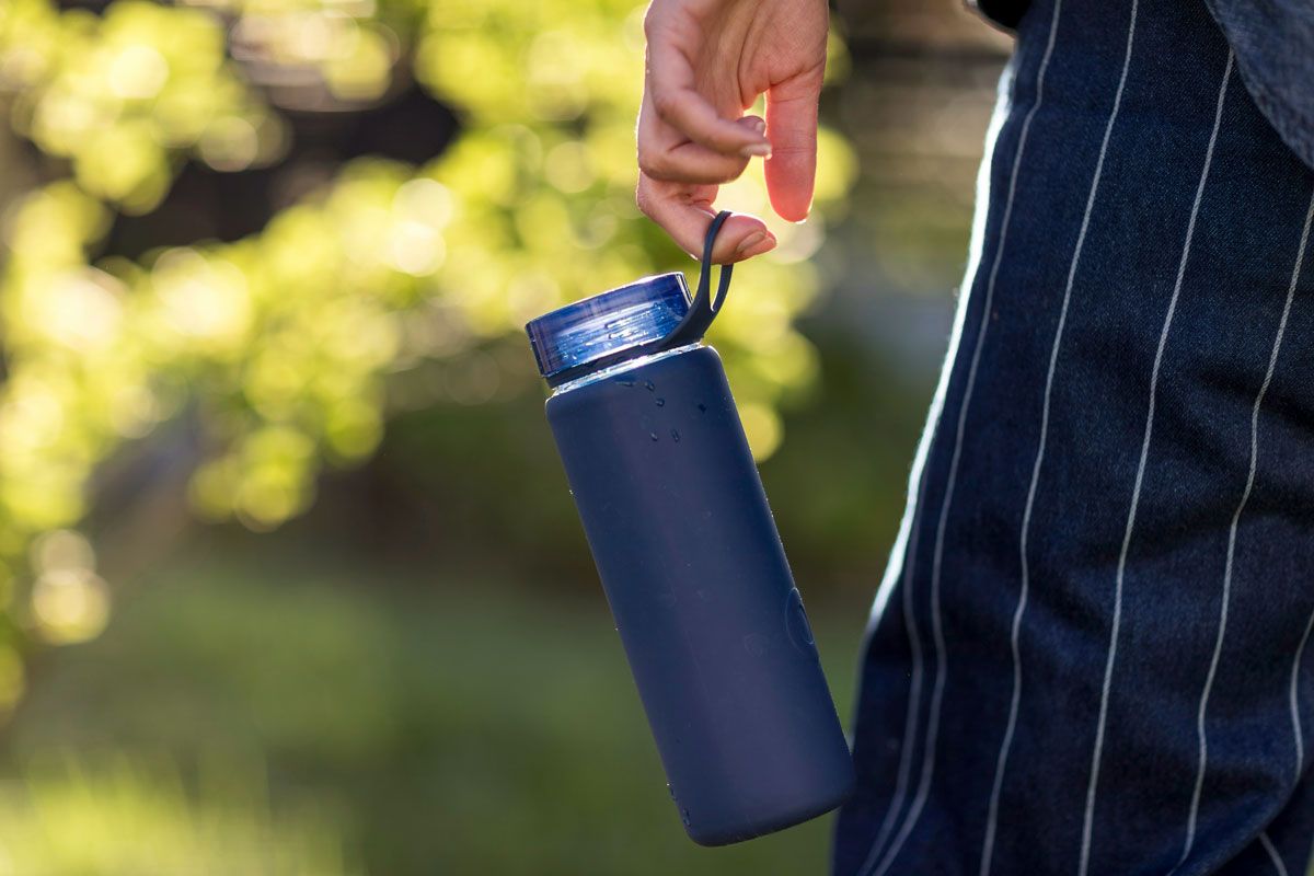 An image of a person holding a blue water bottle on their fingers