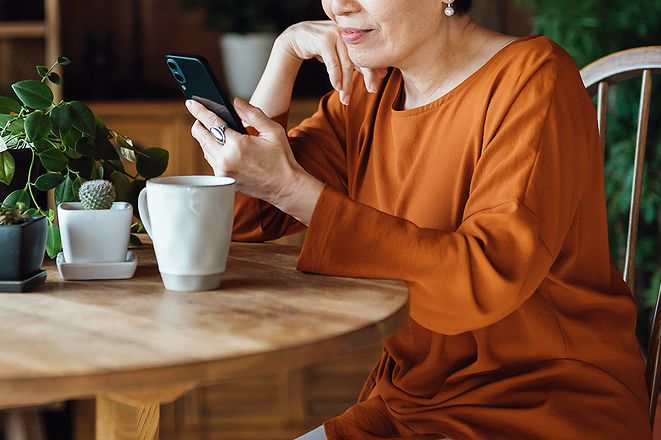 An image of a woman sitting at a table looking at her phone