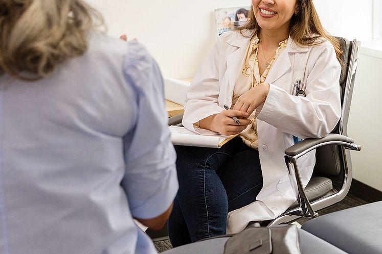 An image of a woman talking to a female doctor sitting in a chair