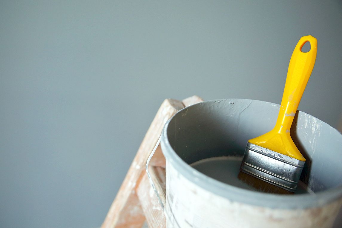 An image of a paint brush in a bucket of blue paint