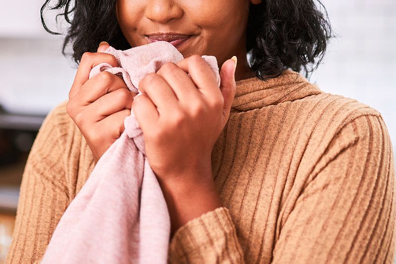 An image of a woman holding a shirt to close to her body