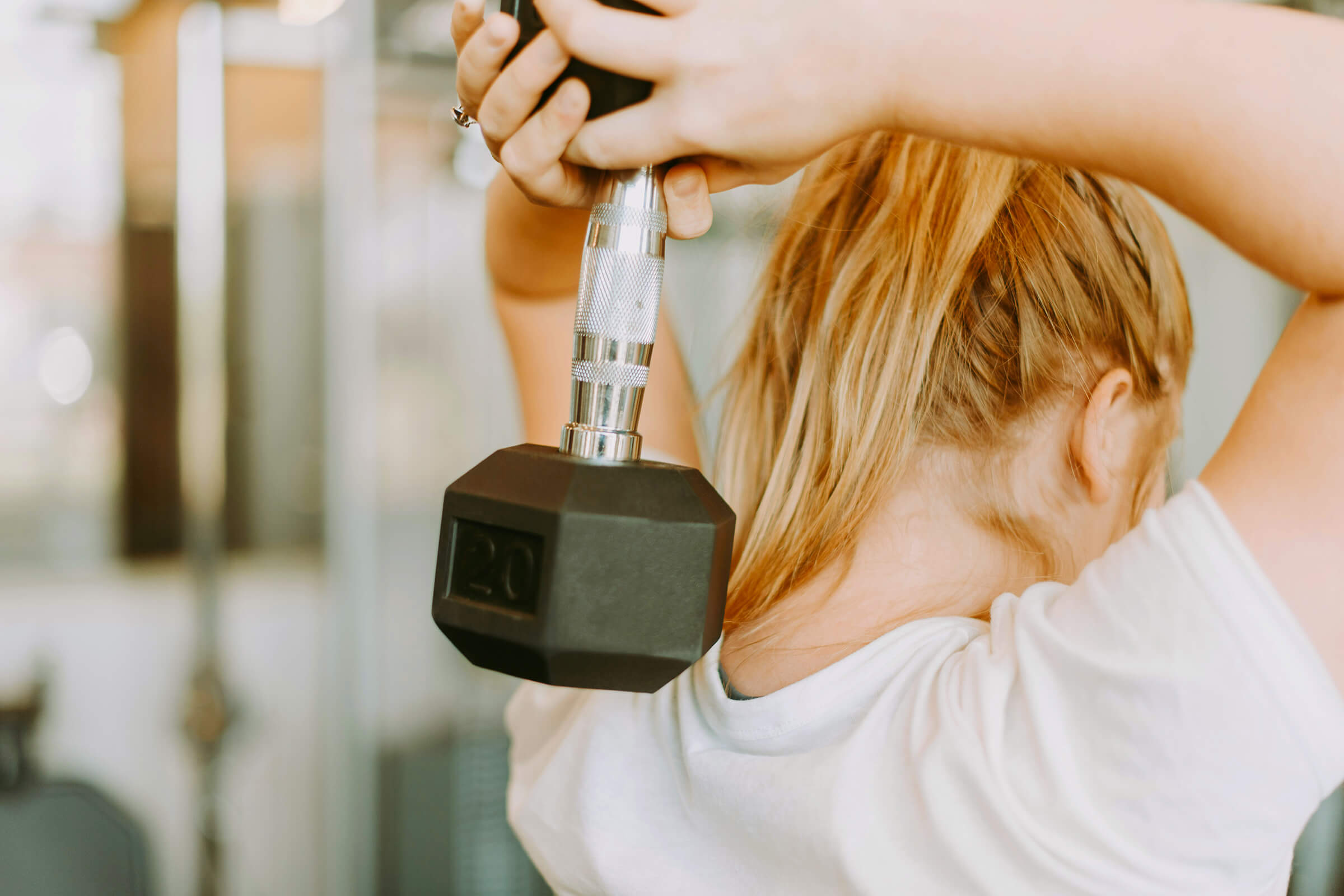 Woman holding a 30-pound weight with both arms behind her head