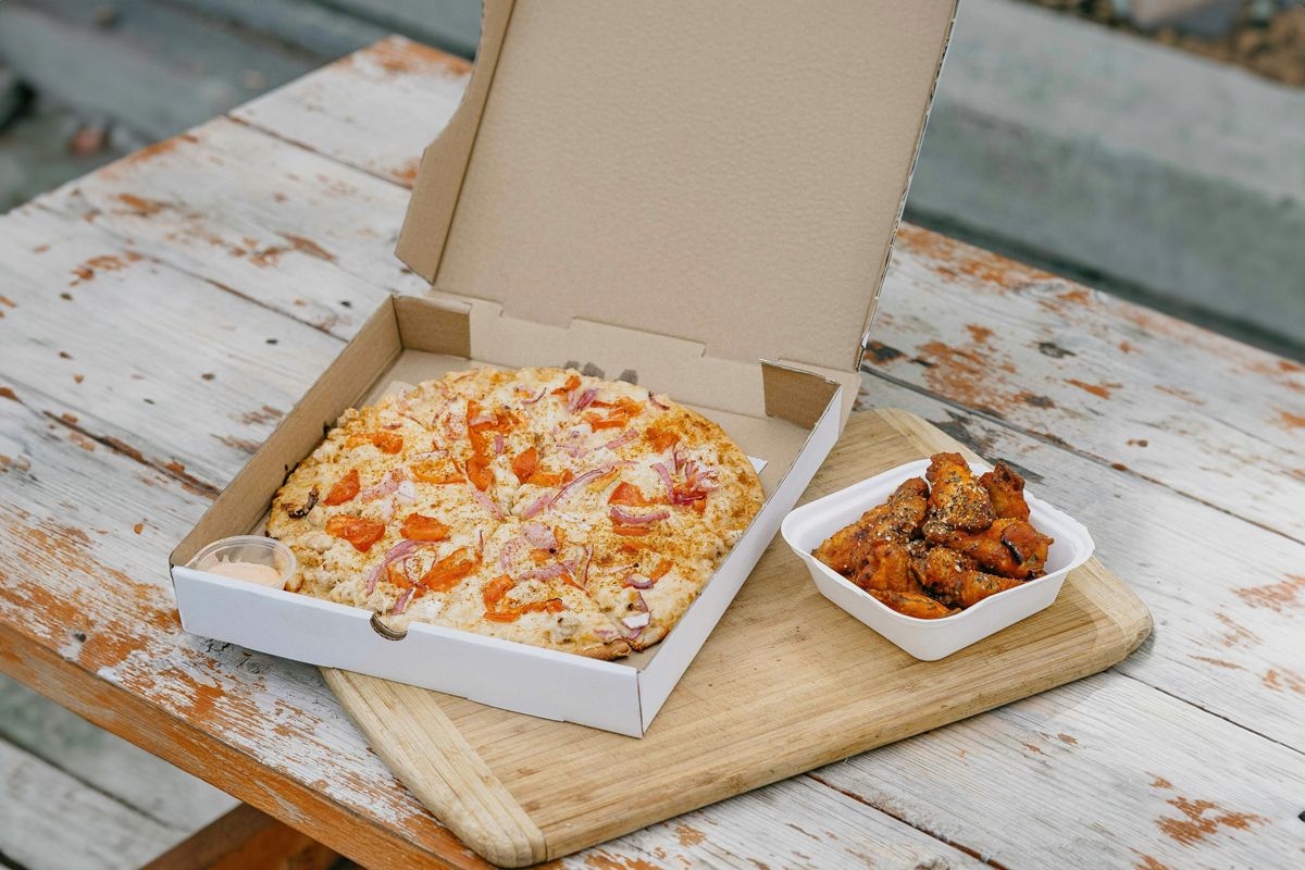 Pizza in pizza box with peppers and onions on it