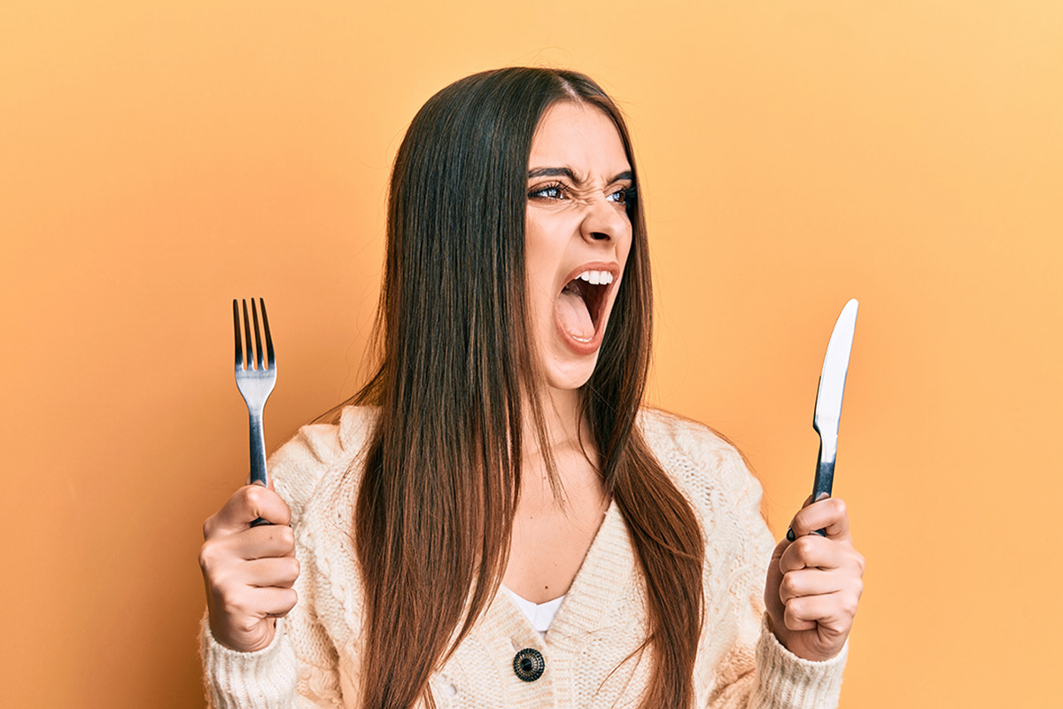 Angry woman holding knife and fork