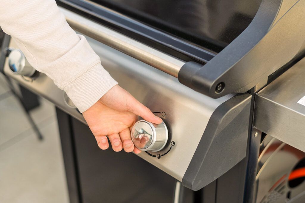 Person turning knob on grill