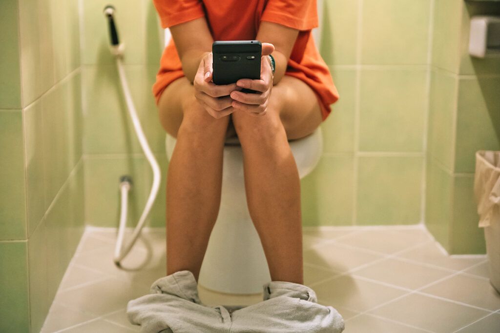 Person on toilet using phone