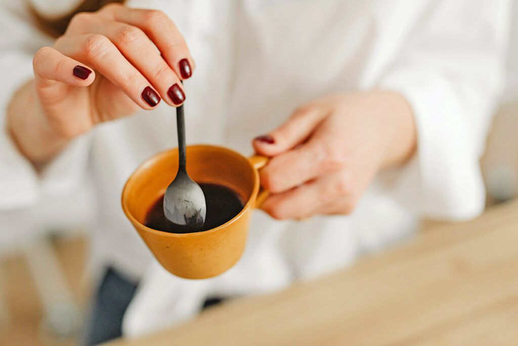 Person stirring coffee with spoon