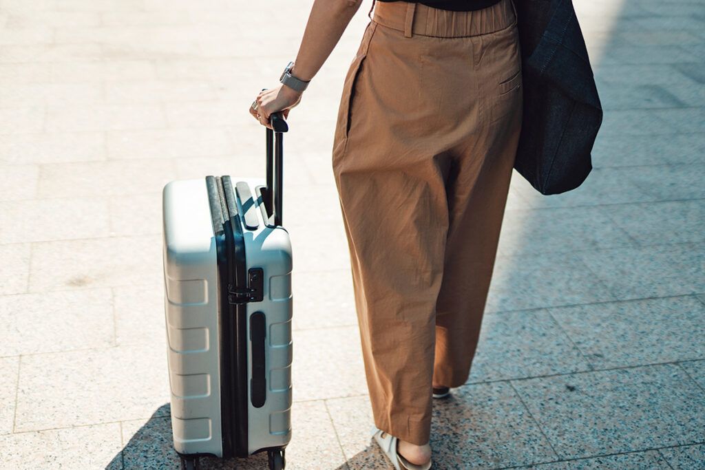 Woman in loose-fitting pants with suitcase