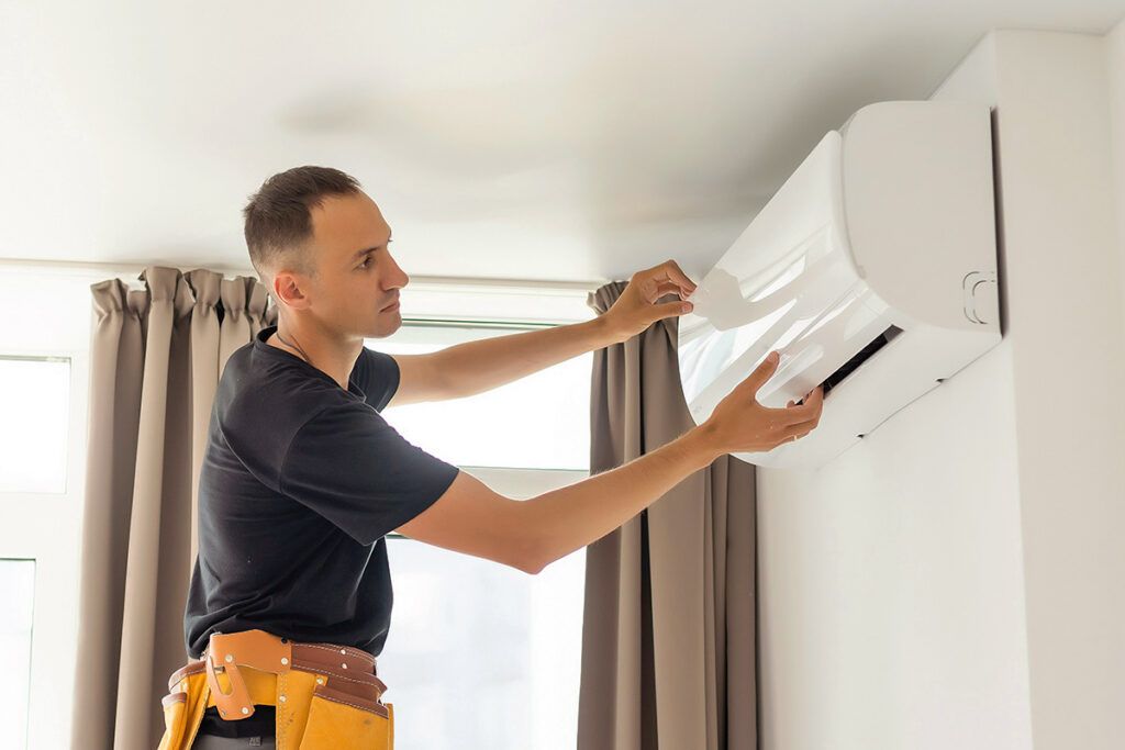 Repairman looking at wall air conditioning unit