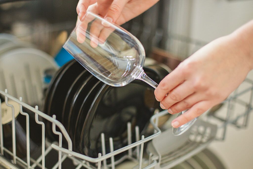 Holding wine glass in front of dishwasher