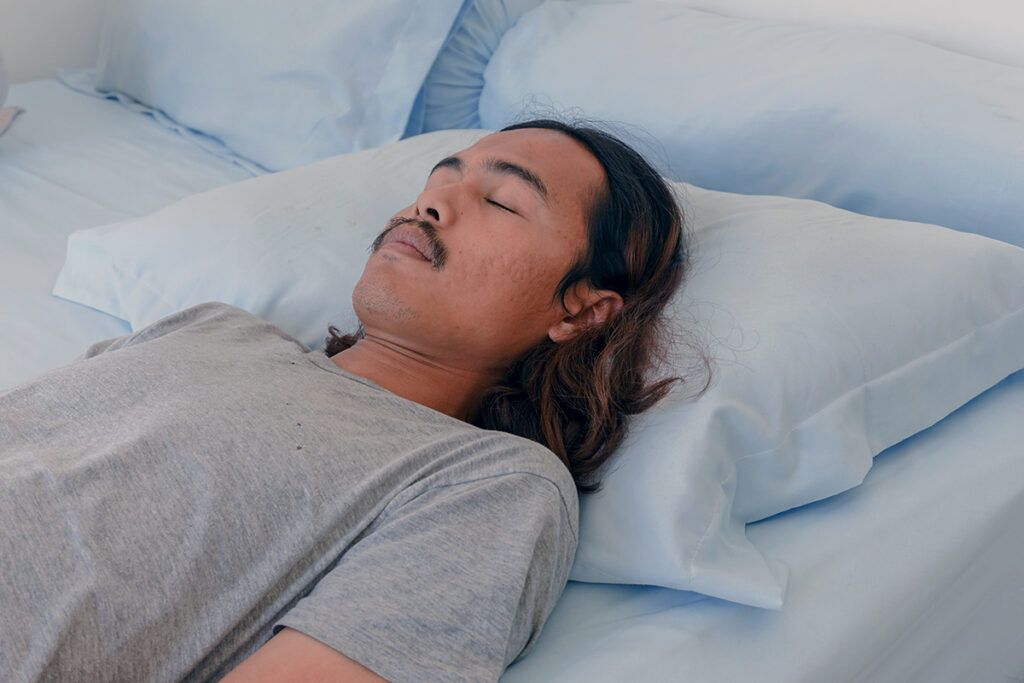 Man with head on pillow, eyes closed