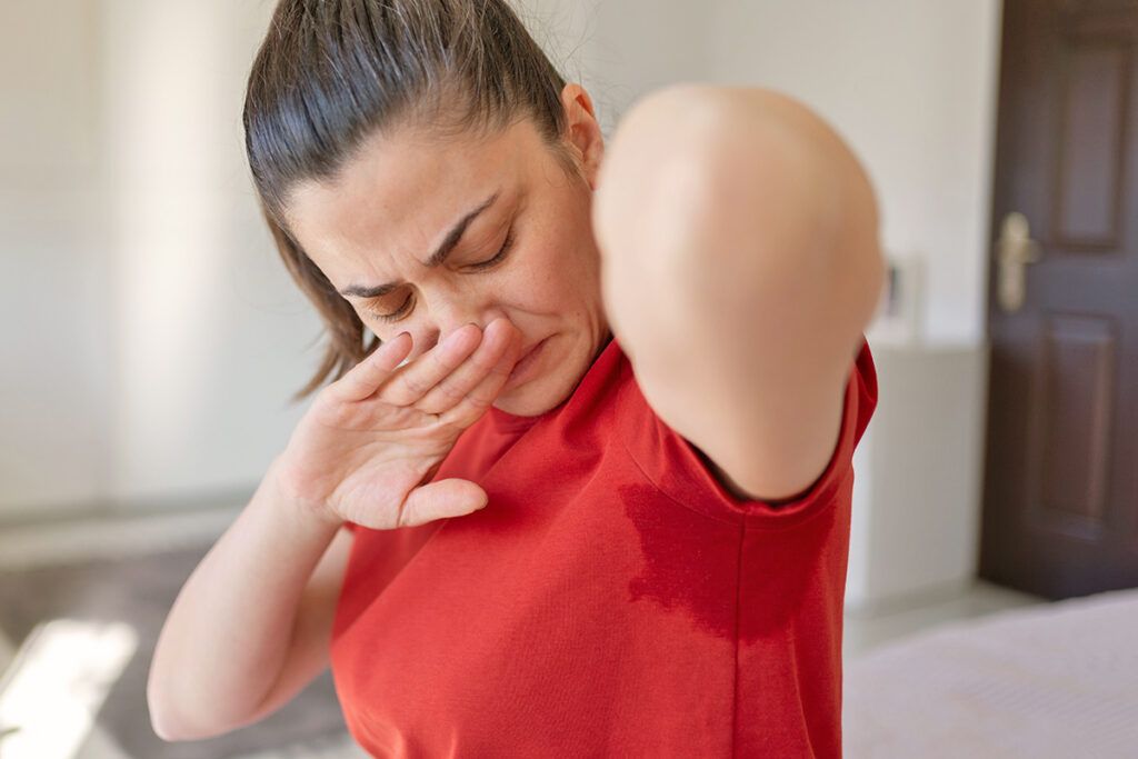 Woman smelling armpit and holding nose