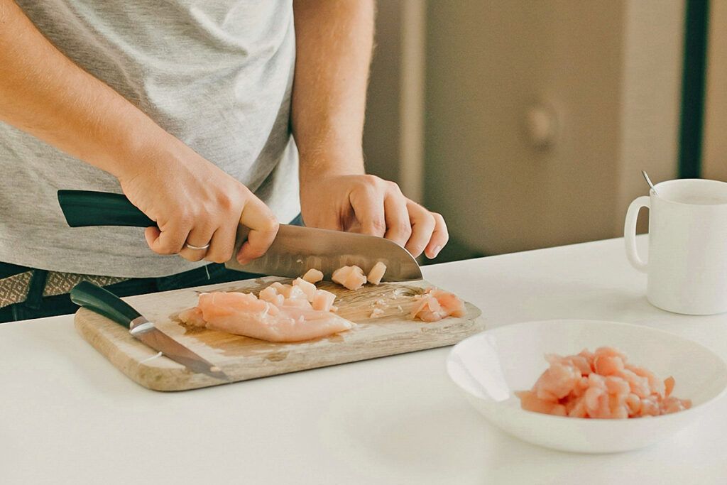 Cutting raw chicken on cutting board