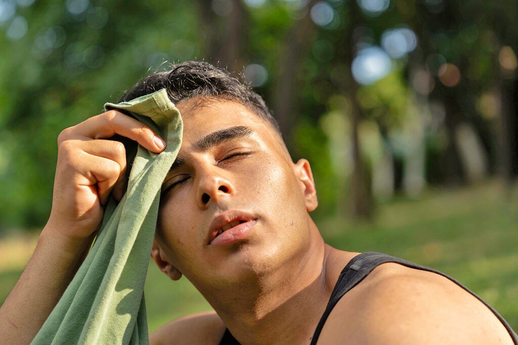 Sweating man wiping brow with cloth