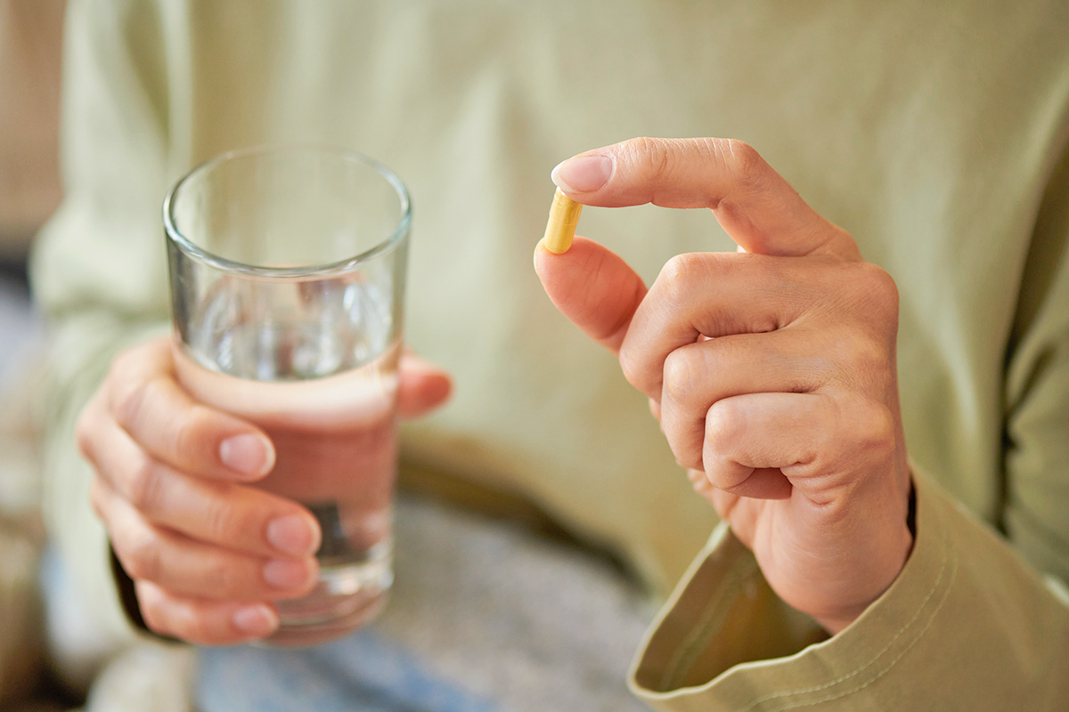 Person holding pill and glass of water