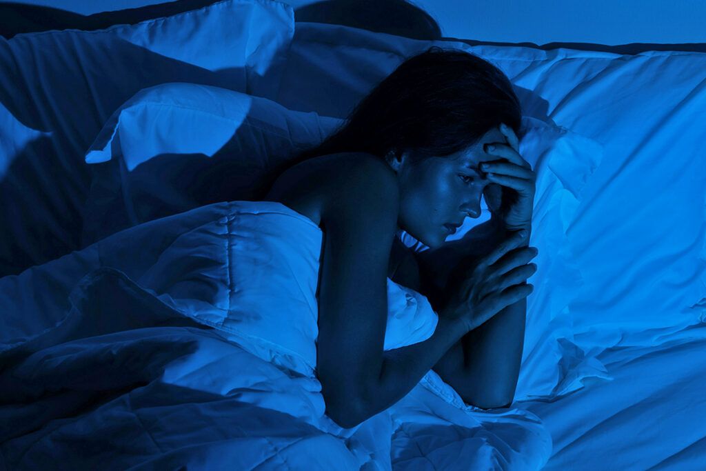 Woman in bed with hand on forehead