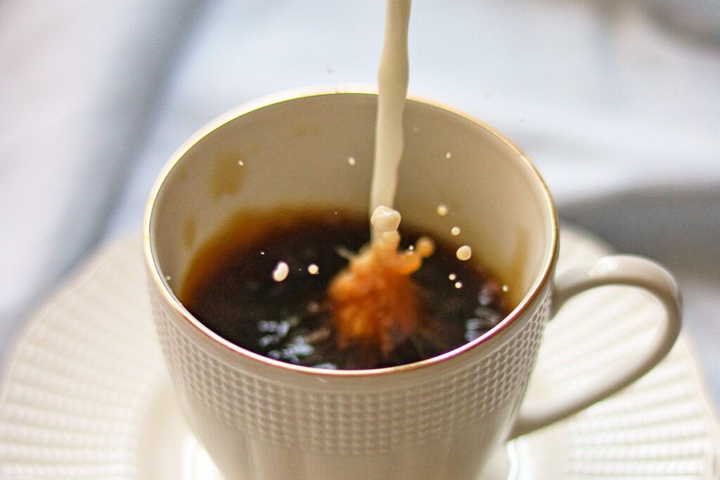 Cup of coffee with milk being poured in