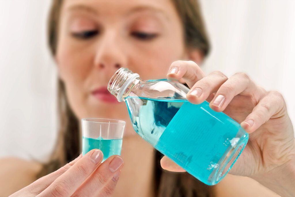 Woman pouring mouthwash into cup