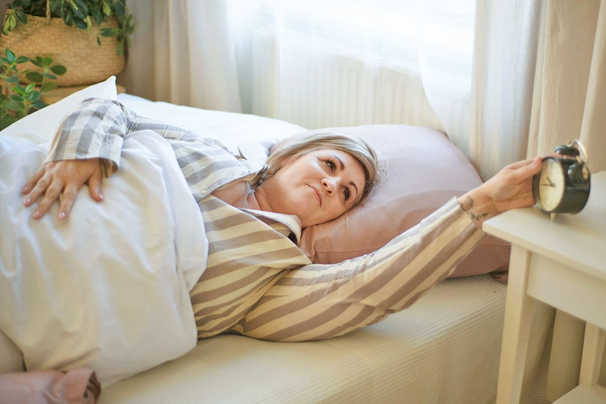 Woman in bed looking at clock