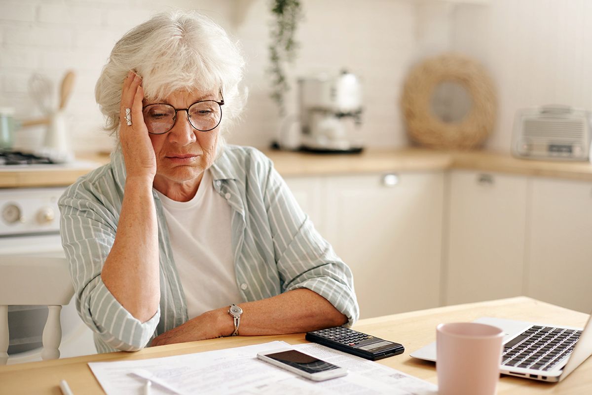 Older woman holding head looking at paperwork