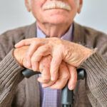 Older man with hands on cane