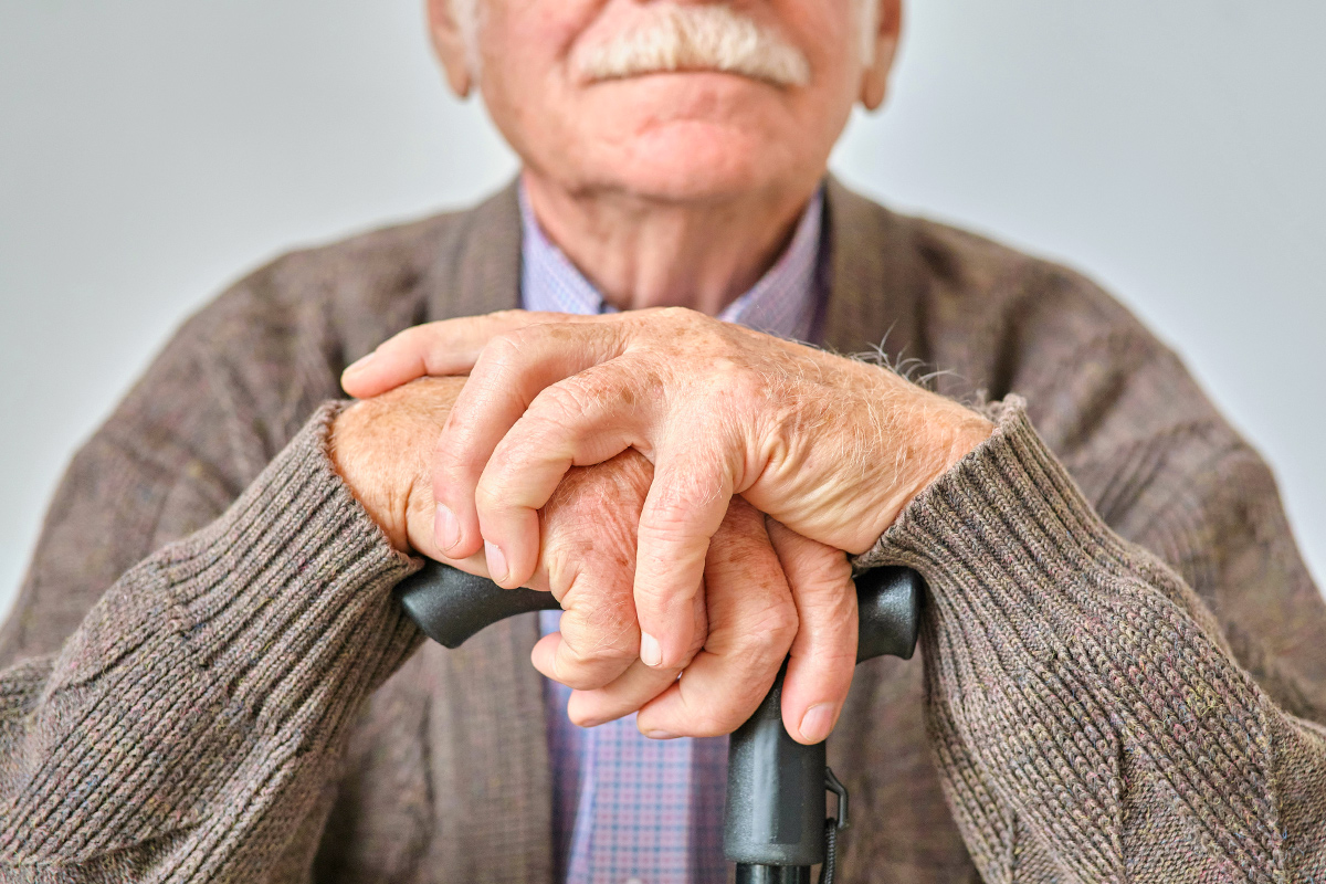 Older man with hands on cane