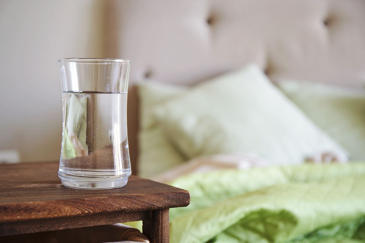 Glass of water on table next to bed