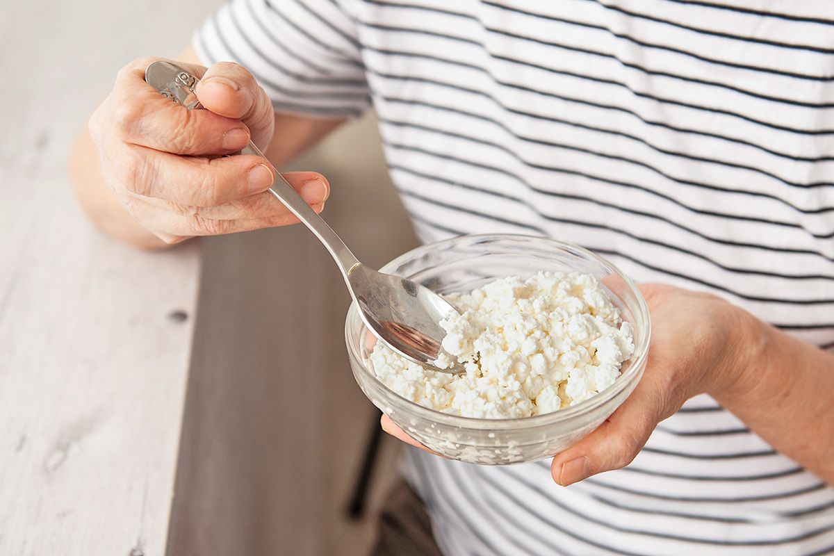 Person holding spoon and bowl of cottage cheese