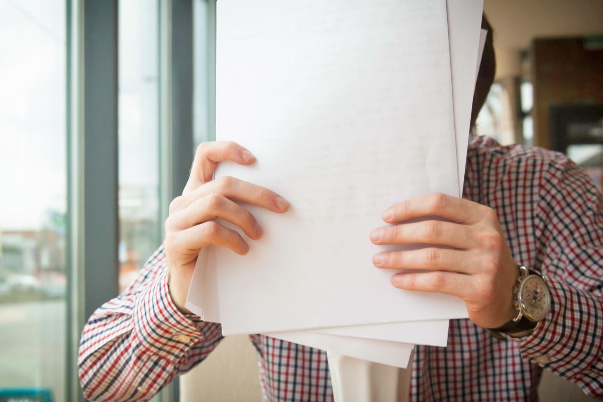 Man holding documents to head