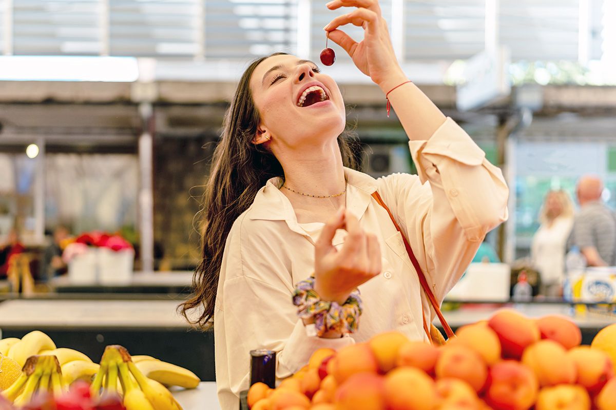 Woman eating cherry at grocery store