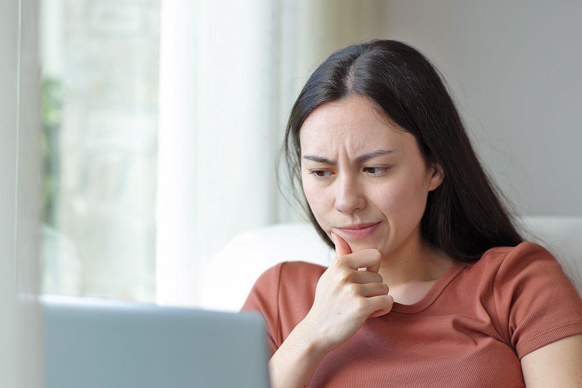 Woman looking at laptop with suspicion