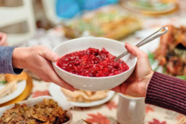 Hands passing cranberry sauce