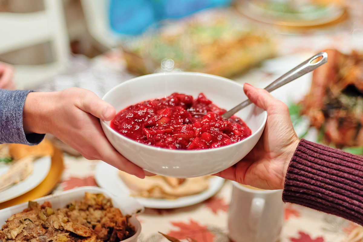 Hands passing cranberry sauce