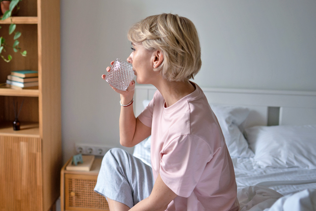 Woman in bed drinking water