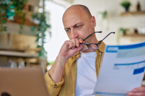 Man holding bill looking at computer
