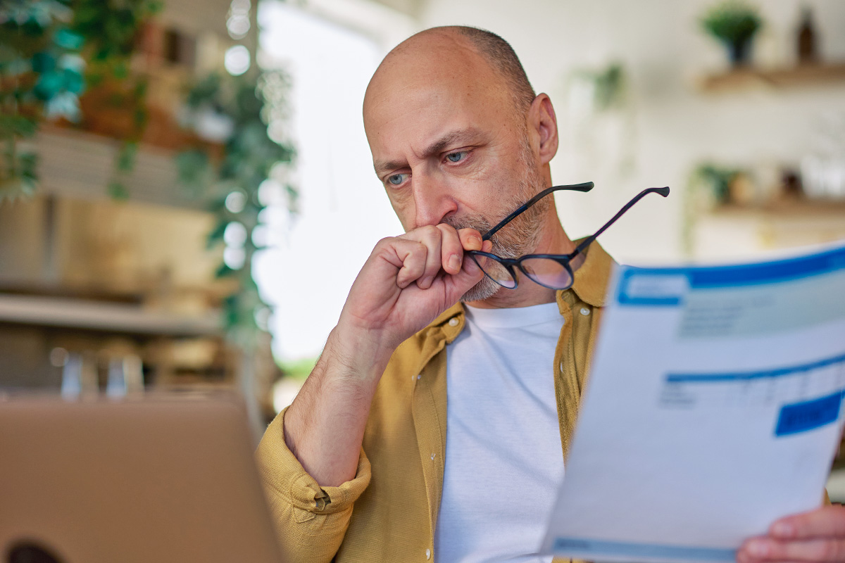 Man holding bill looking at computer